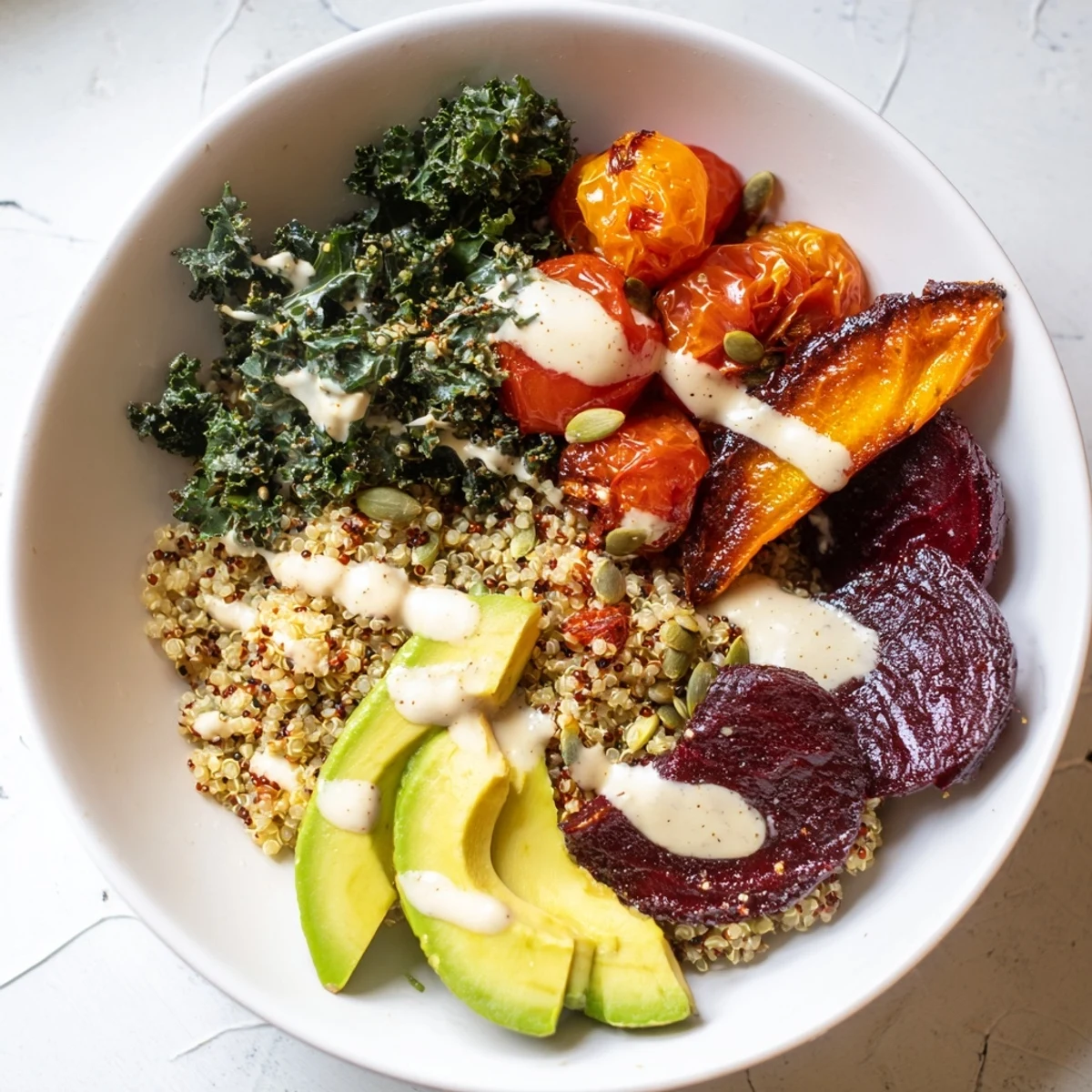 Close-up of a colorful quinoa, kale and roasted beet bowl, glistening tahini drizzled on top!