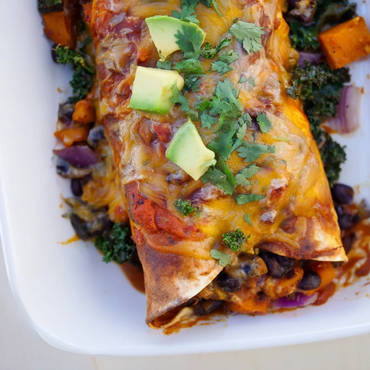 One-pan sweet potato, black bean & kale enchiladas baking with bubbly cheese, a delicious, layered main dish.