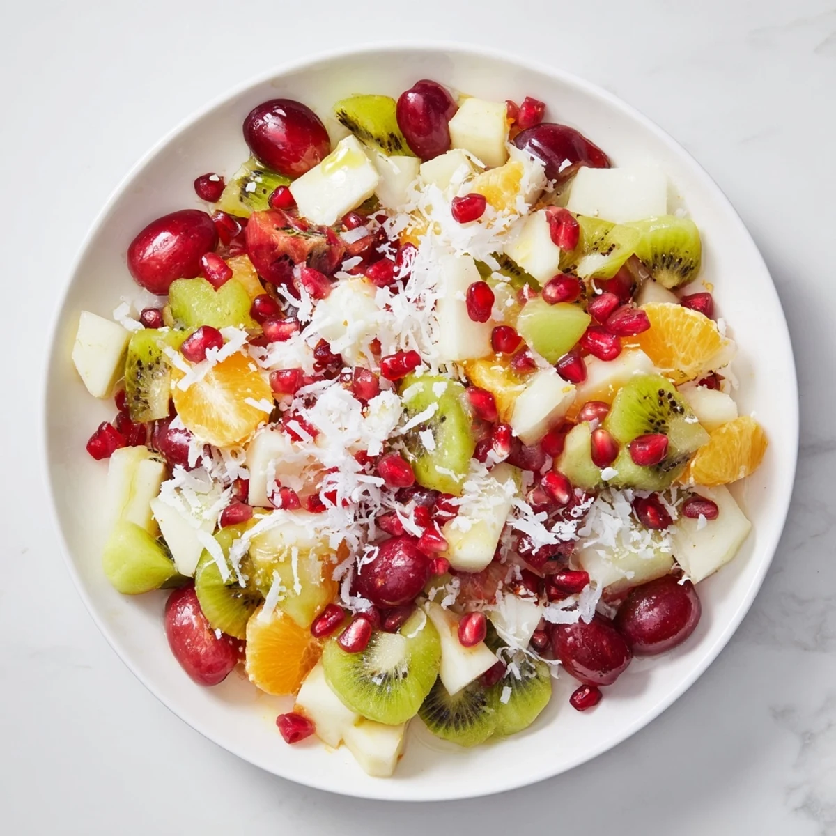 Vibrant Snowflake Fruit Medley, a colorful winter salad with glistening citrus dressing and coconut snow.
