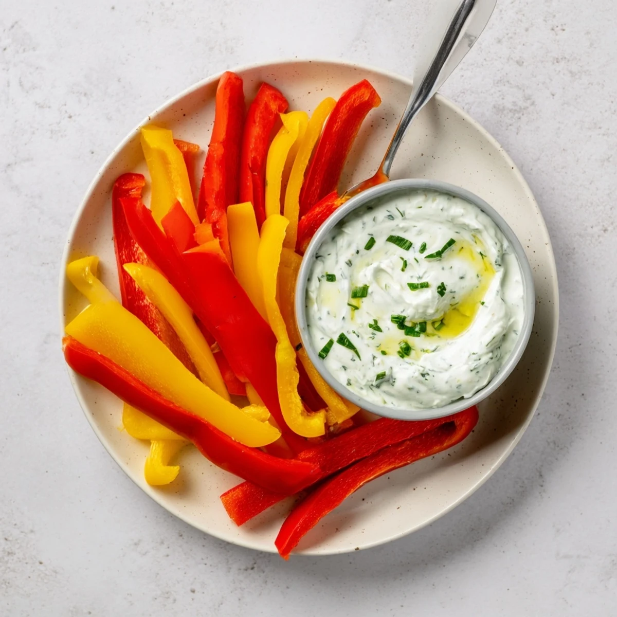 Vibrant bell pepper strips and cool, creamy Greek yogurt dip, a healthy snack option.