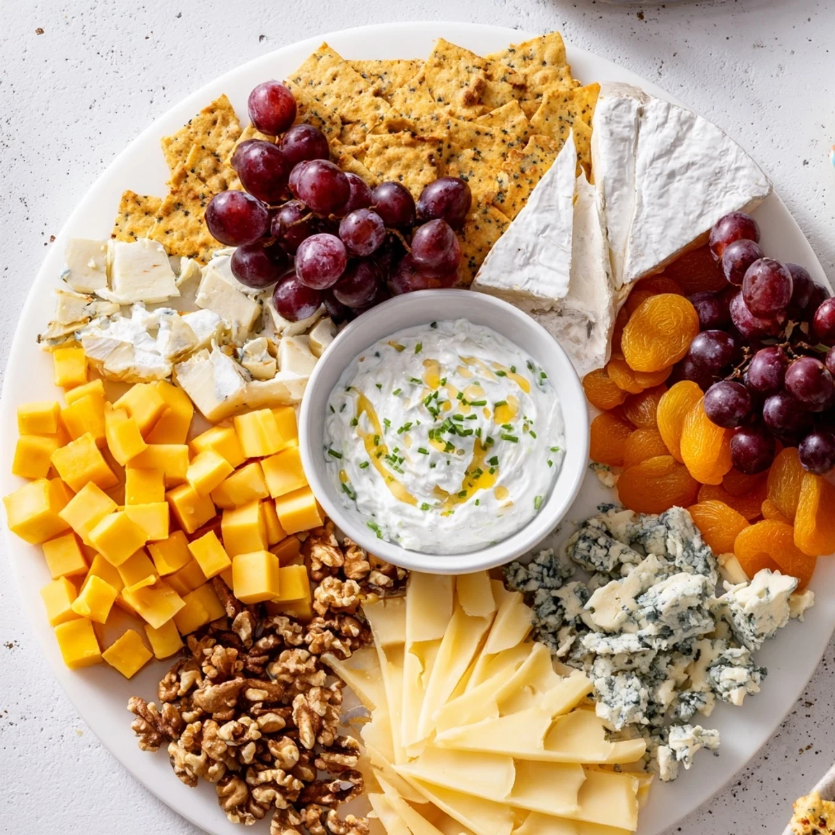 The Celtic Cross Cheese Platter features a creamy central dip surrounded by assorted cheeses and fruits.