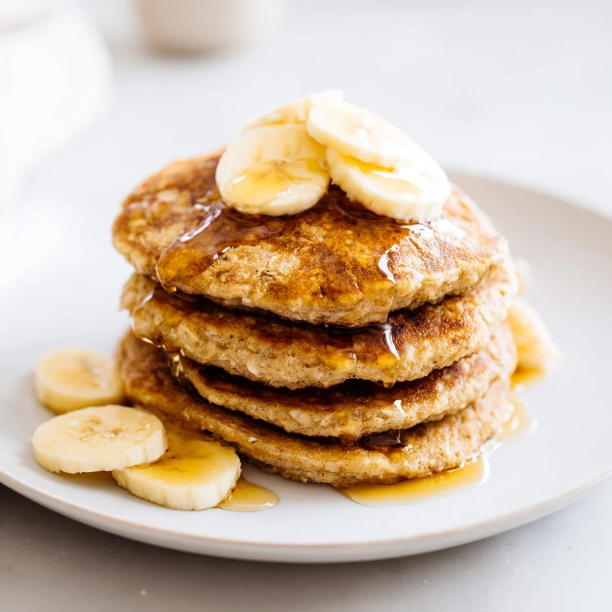 Golden-brown banana oat pancakes stacked high, ready to be drizzled with maple syrup.