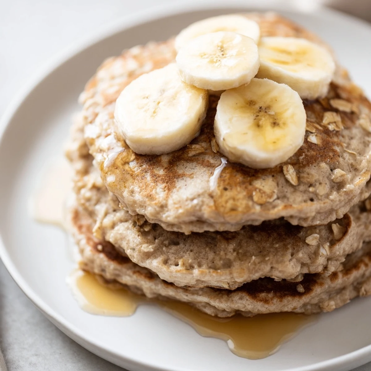 Close-up of freshly cooked banana oat pancakes, showcasing their soft, textured surface.