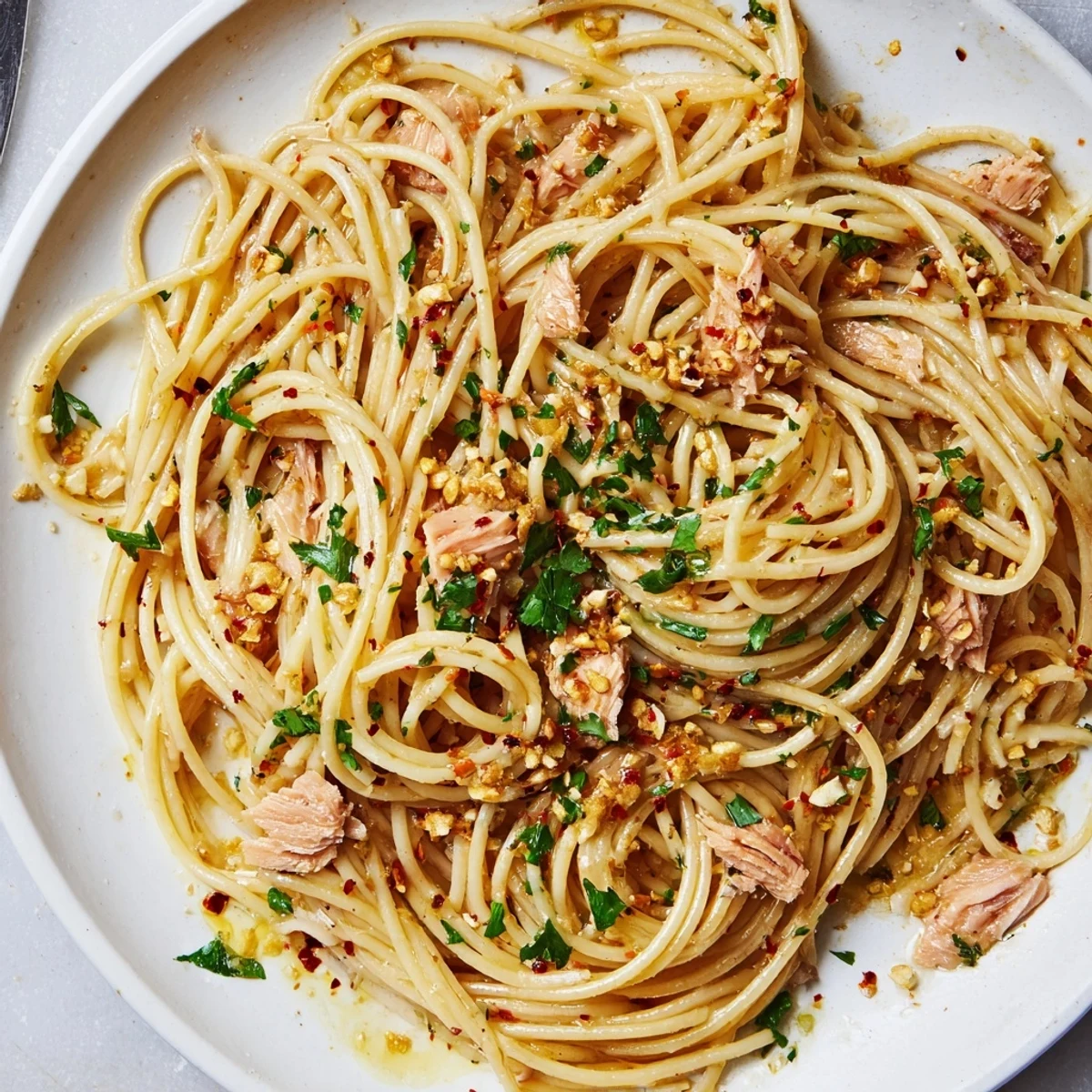 Bright, zesty Lemon-Garlic Tuna Spaghetti is tossed with parsley, served with fresh lemon wedges.
