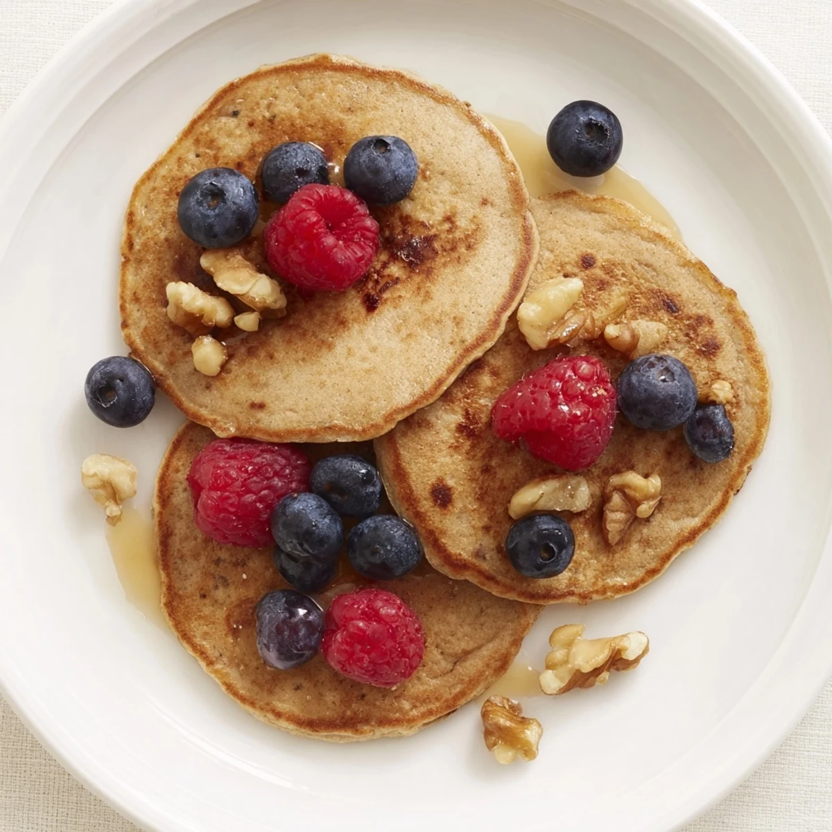 A stack of warm banana pancakes, topped with fresh berries, offer a delightful and healthy treat.