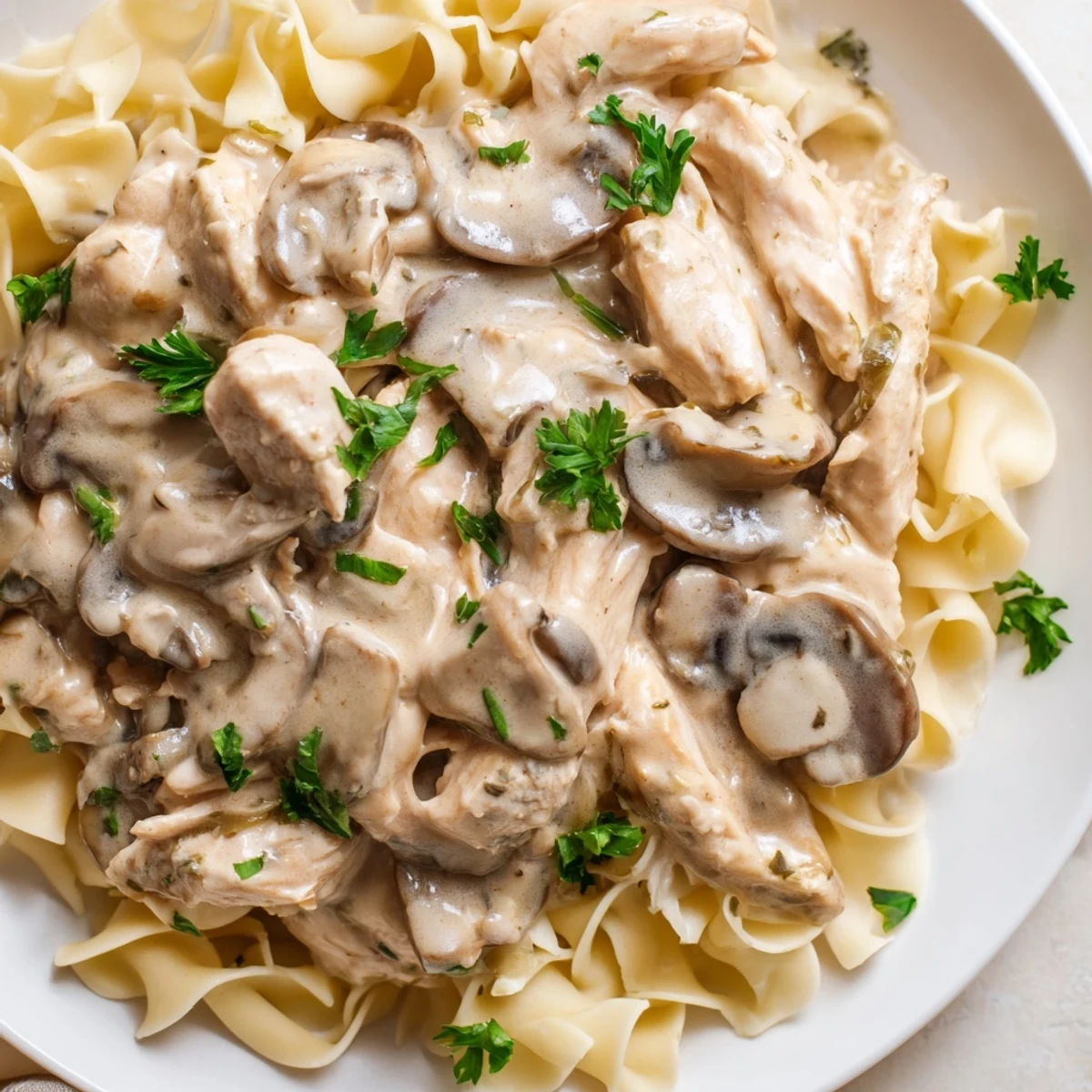 Hearty Chicken and Mushroom Stroganoff over egg noodles, ready to serve with a side of green beans.