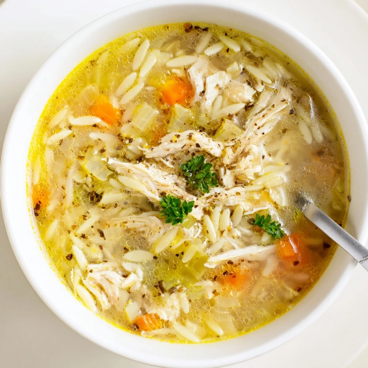 Vibrant Lemon Pepper Chicken Orzo Soup featuring tender chicken and orzo pasta in a clear broth.