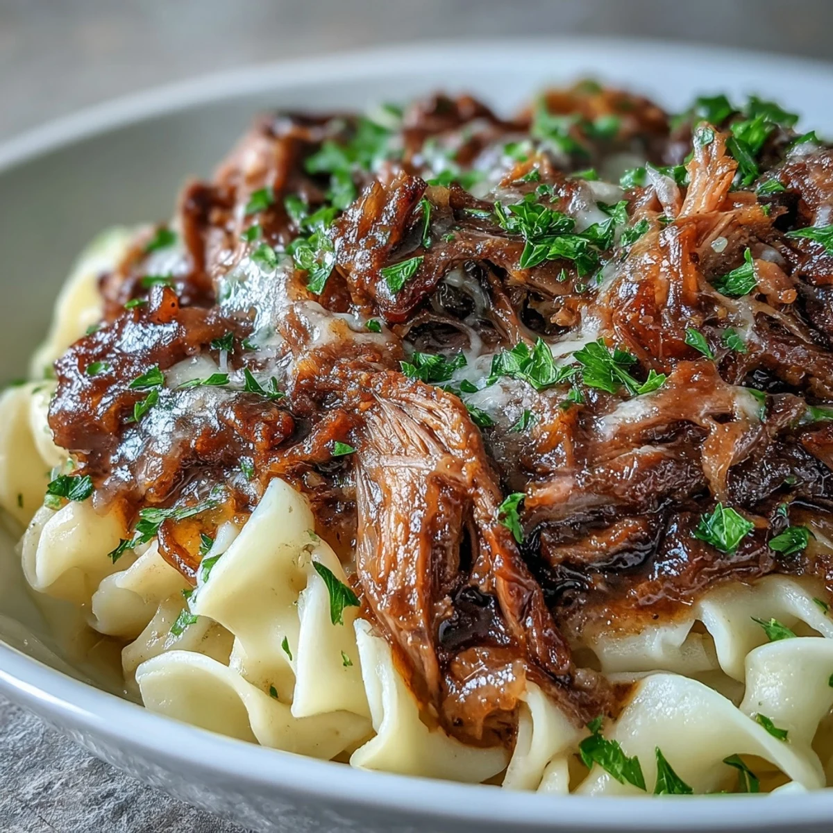 Slow-cooked Crockpot French Onion Pot Roast Pasta features tender shredded beef, caramelized onions, and rich gravy ladled over buttery egg noodles.