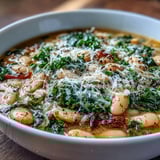 Creamy cannellini beans and tender kale simmer in a rich Parmesan broth, served with crusty bread for a hearty meal.
