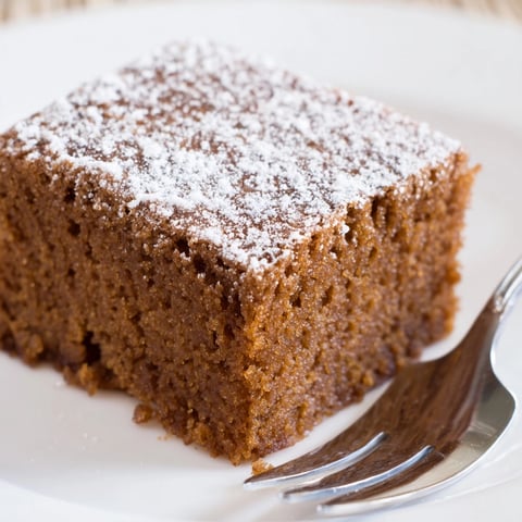 Golden Cinnamon Gingerbread Snack Cake slices, dusted with powdered sugar; warm, inviting aroma.