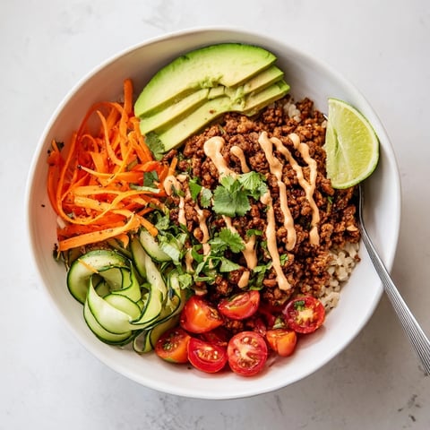 A colorful plant-based meat bowl topped with fresh vegetables and zesty lime.  