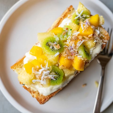 Vibrant yogurt-custard toast topped with tropical fruits for a refreshing brunch.  