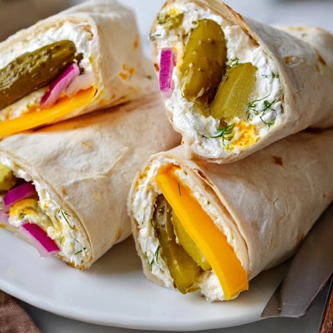 Crisp pickle-in-a-blanket rolls with creamy cheese, perfect for appetizers at parties.  