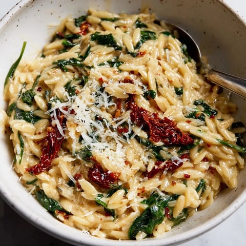 A creamy Tuscan orzo bowl with sun-dried tomatoes and fresh spinach.  