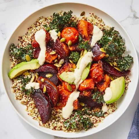 Warm, vibrant quinoa, kale & roasted beet bowl, topped with creamy tahini dressing, ready to eat.