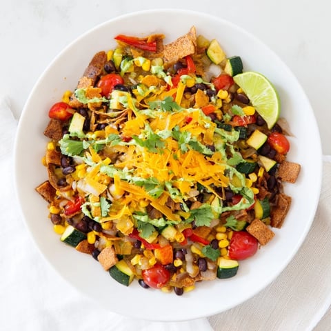 Steaming Veggie-Packed Taco Skillet with Avocado Yogurt topped with fresh cilantro and a lime wedge.