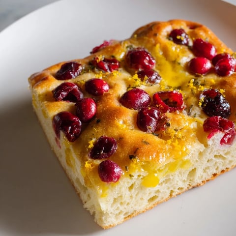 Golden-brown cranberry orange no-knead focaccia with glistening cranberries and crispy, dimpled top.