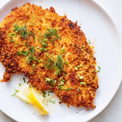 Golden-brown Pickle-Brined Chicken Cutlets, served with fresh dill and lemon wedges, look irresistibly crunchy.