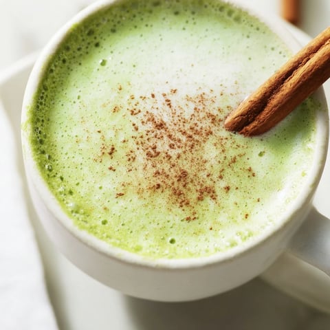 Steaming Maple Cinnamon Gingerbread Matcha Oat Latte with a garnish of cinnamon, ready to warm your soul.