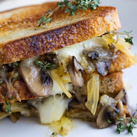 Golden, gooey Roast Garlic Mushroom & Thyme Grilled Cheese, oozing with melted Gruyère, ready to savor.