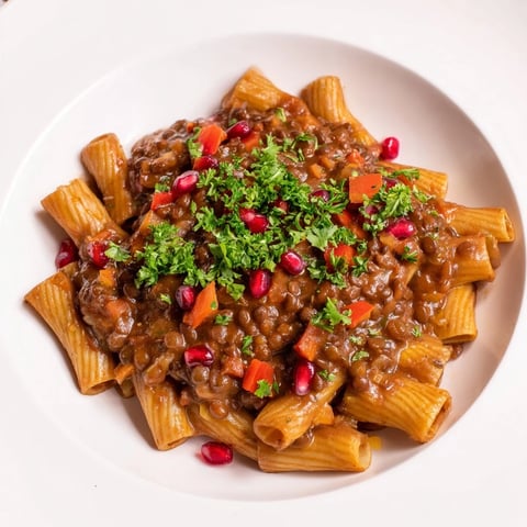 Steaming bowl of High-Fiber Lentil Bolognese pasta with fresh parsley and Parmesan cheese, ready to serve.