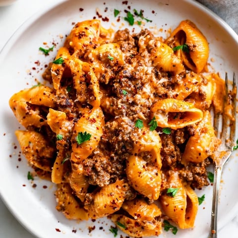 One pot creamy beef and shells in a skillet, steam rising from the rich tomato sauce and melted cheese.  