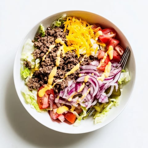A close-up of Easy Big Mac in a Bowl with seasoned ground beef, crisp lettuce, and melted cheddar.