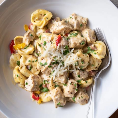 A vibrant bowl of Zesty Cajun Garlic Parmesan Chicken Tortellini with savory spices and cheese.  