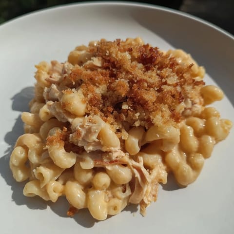 A close-up of baked classic mac & cheese with BBQ chicken, golden crust with savory chicken visible.