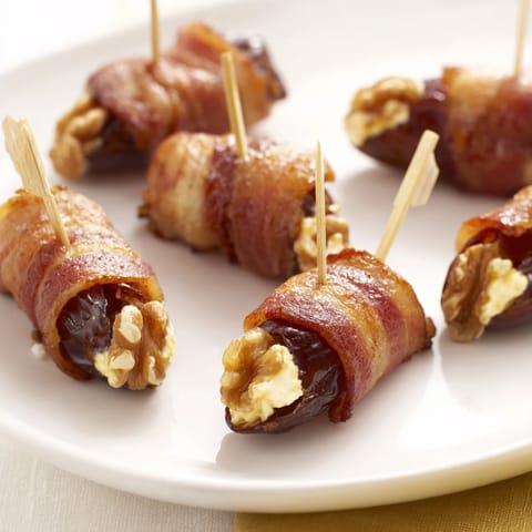A close-up of sizzling bacon-wrapped dates; a delightful bite of sweet, salty, and creamy goodness.