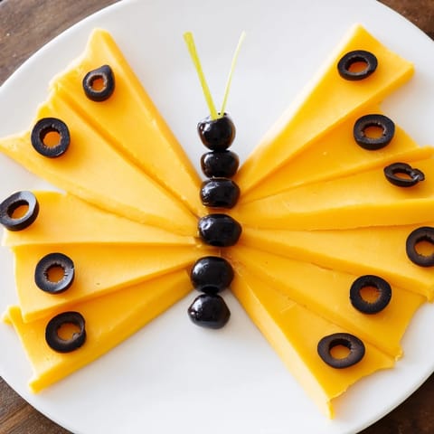 Black olive details and cheese wings create a colorful Butterfly Migration appetizer perfect for kids.
