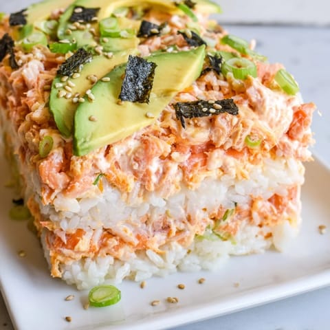 A close-up of a delicious sushi bake casserole, ready to serve with soy sauce and nori.