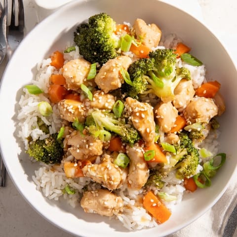A close-up view of One Pan Honey Garlic Chicken Broccoli Rice garnished with green onions and sesame seeds.