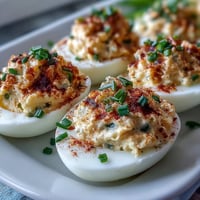 Classic Deviled Eggs with Paprika and Chives, creamy yolk filling topped with smoky paprika and fresh chives.