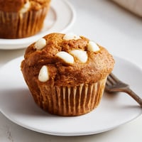 Moist pumpkin muffins with white chocolate chunks nestled in warm autumn spices.  
